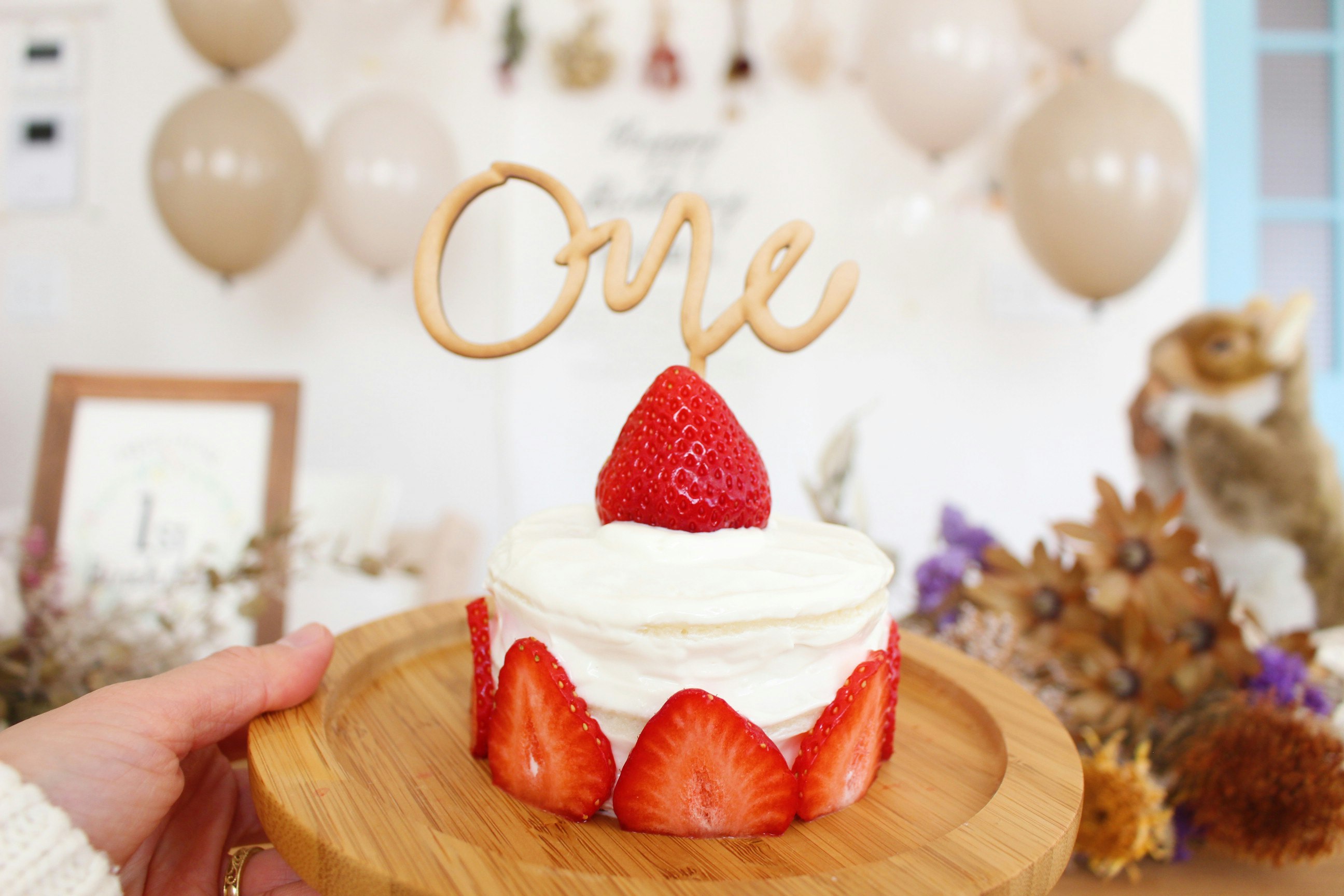 kue mini stroberi di atas piring kayu dengan tangan