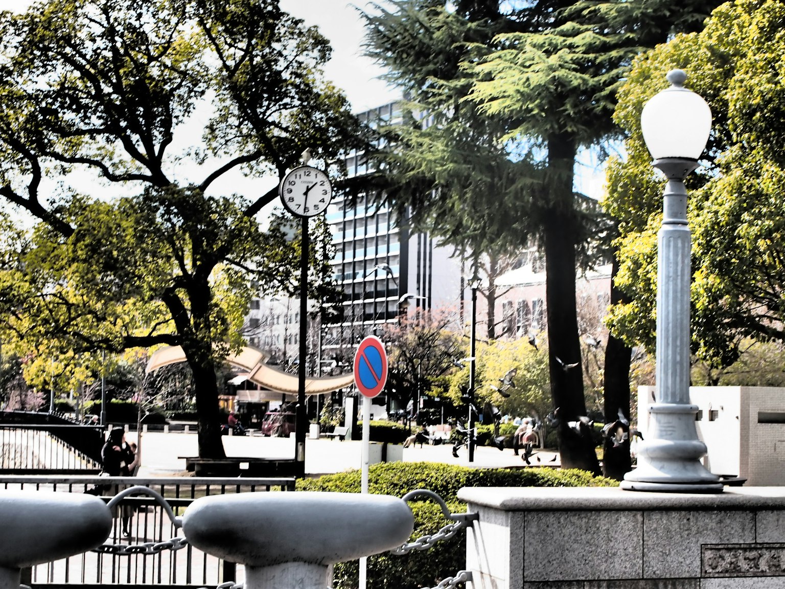 公園場景，路燈和時鐘，周圍有樹木和建築物