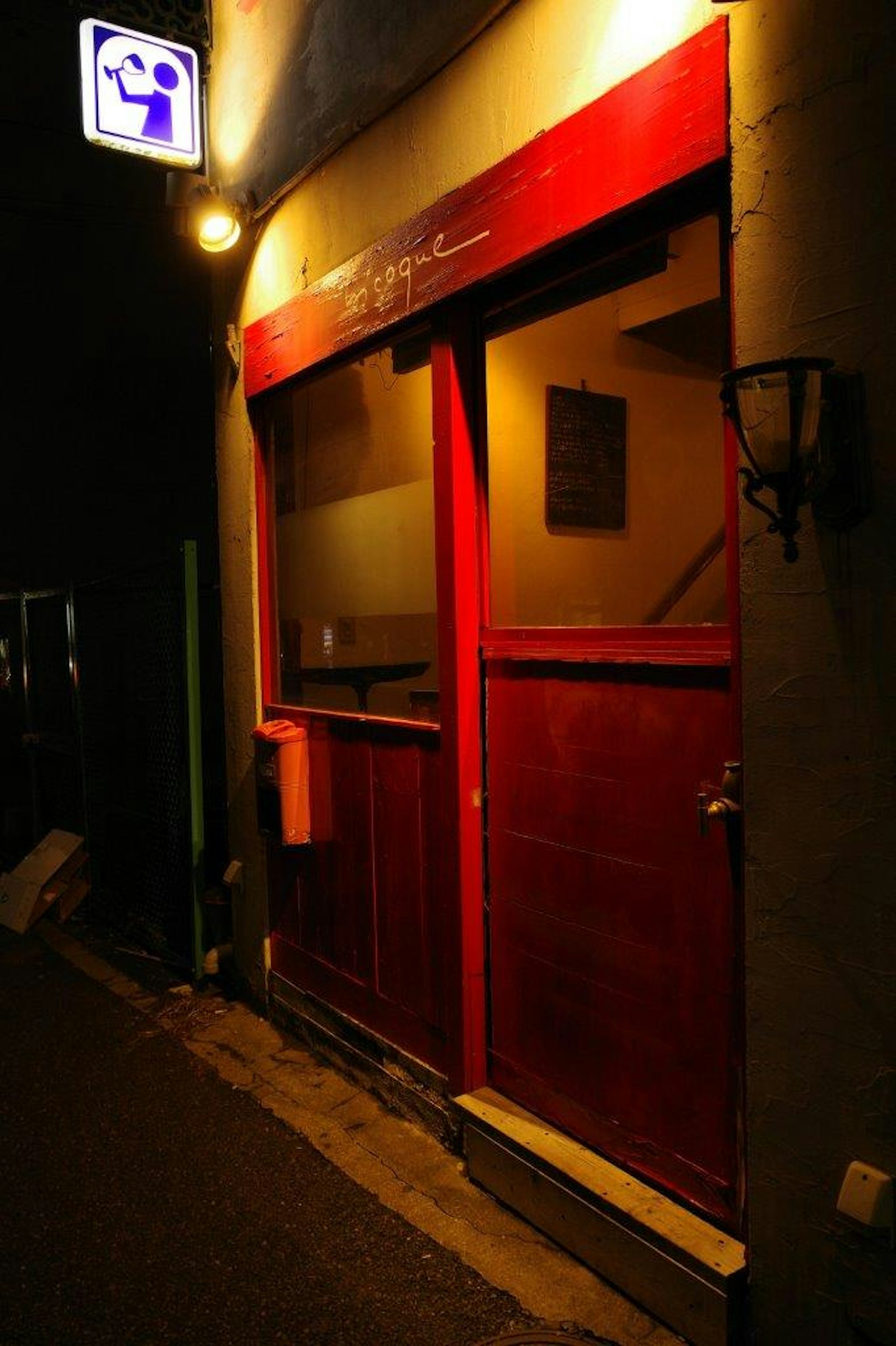 Foto de la entrada de una tienda con puerta roja de noche