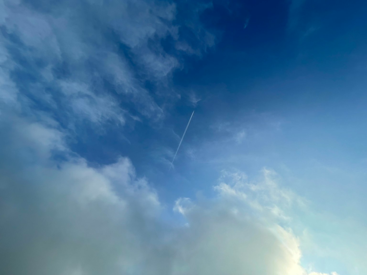 Langit biru dengan awan putih dan jejak pesawat yang terlihat
