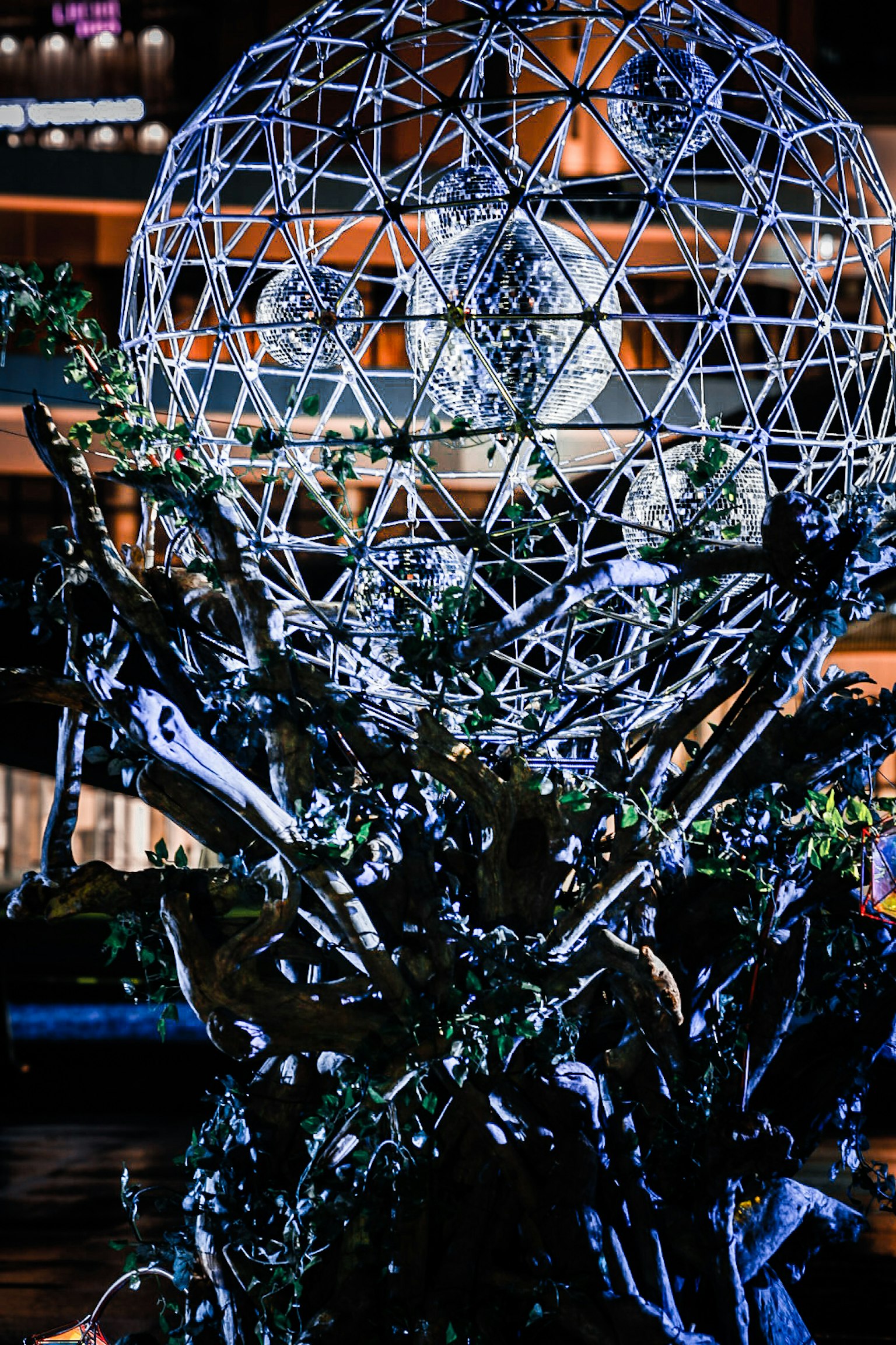 Dekorative Kunst mit einer geometrisch gemusterten Kugel und Grünpflanzen