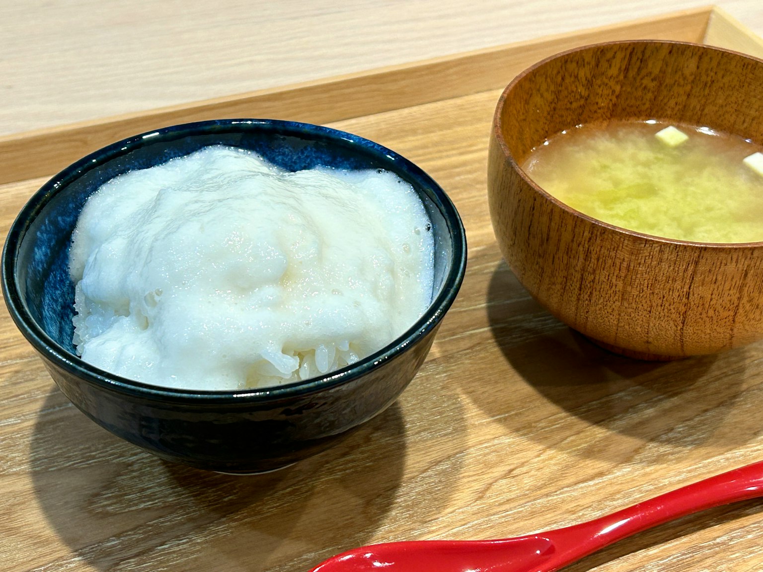 Mangkuk nasi putih dan cangkir kayu sup miso di atas nampan kayu