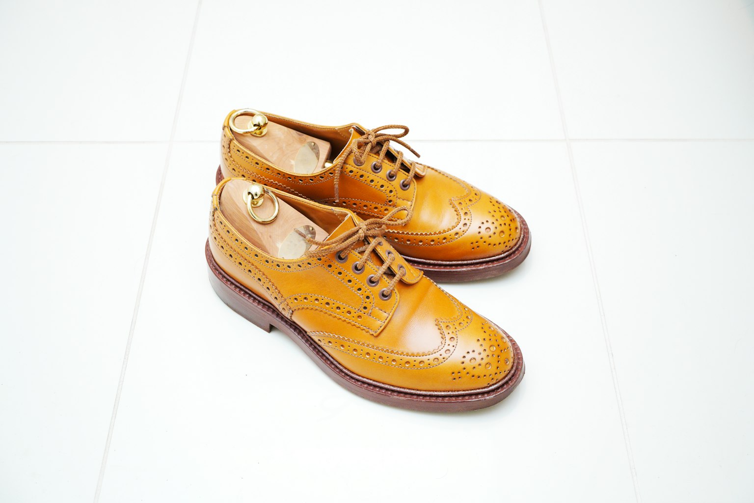 Tan leather shoes with intricate detailing on a white background