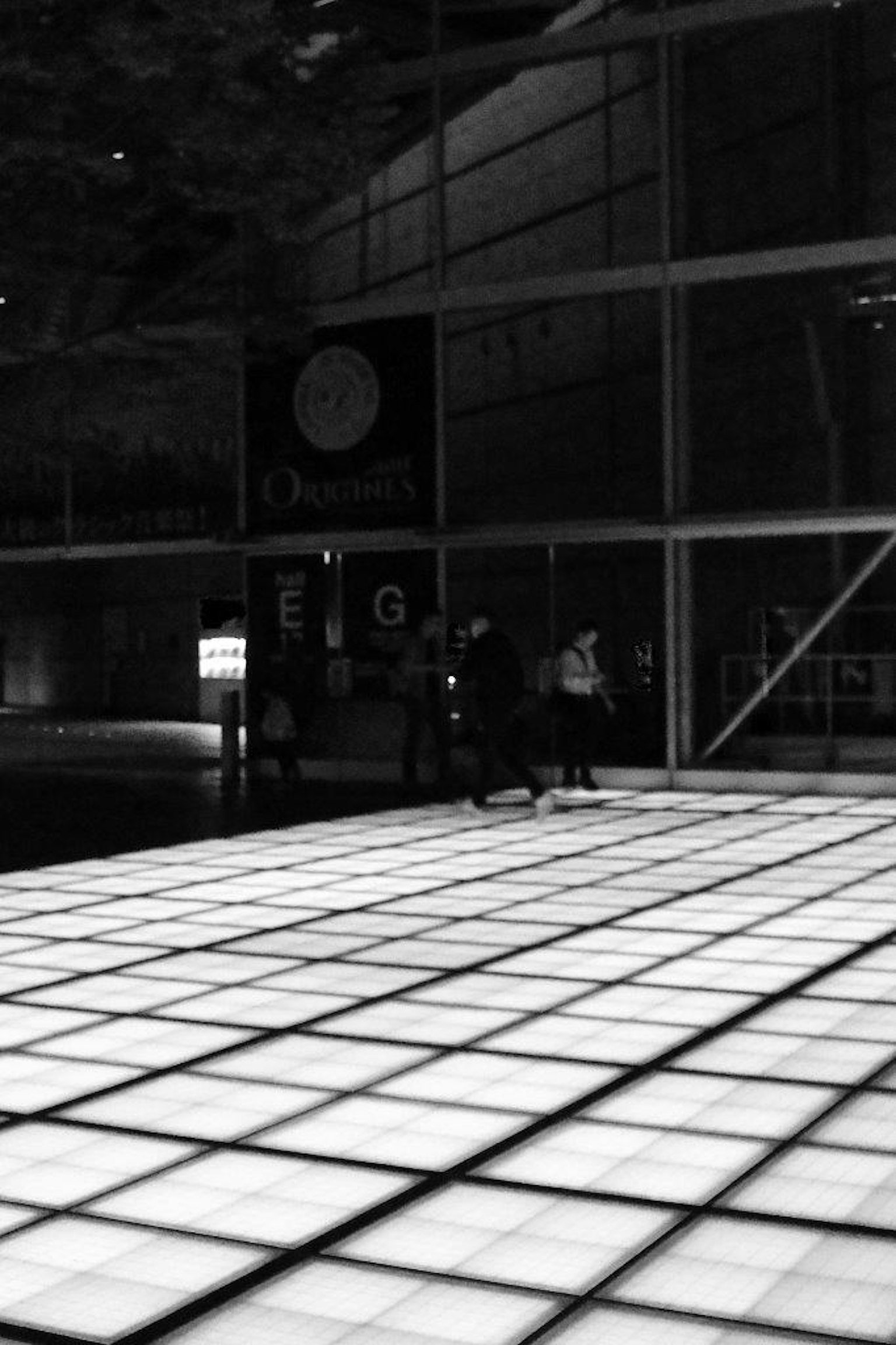 Spazio interno moderno con persone che camminano su un pavimento a piastrelle bianco e nero